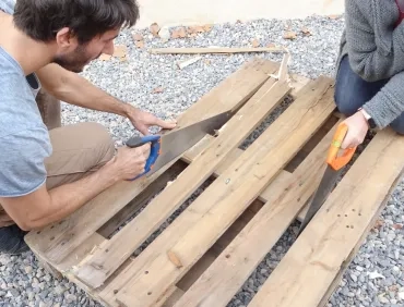 Deux adultes scient une palette