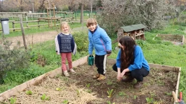 Deux enfants et leur animatrice sont dans un jardin