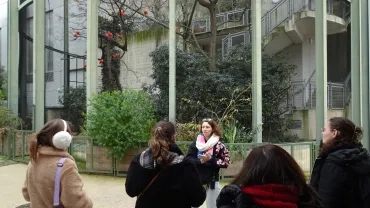 un groupe d'adulte devant une animatrice, en arrière plan une cage remplie d'Ibis rouge