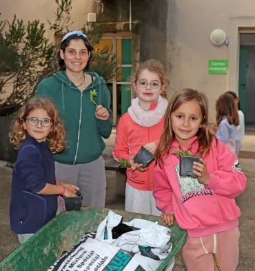 Un groupe d'enfants et leur animatrice mettent du compost dans des godets