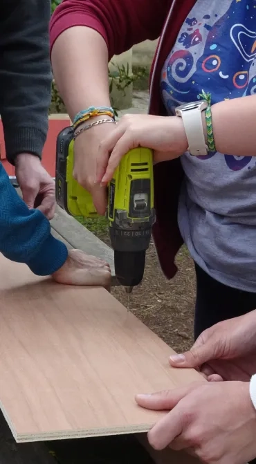 Une adulte visse une planche de bois