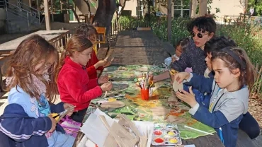 Un groupe d'enfants et leur animatrice découpent et peignet du carton