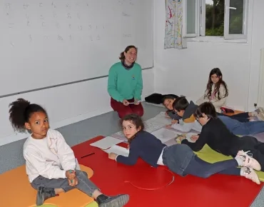 un groupe d'enfant allongé par terre écrit des lettres japonaises