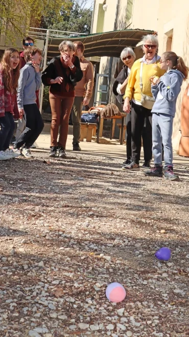 un groupe d'adultes séniors et d'enfants jettent des boules en plastique