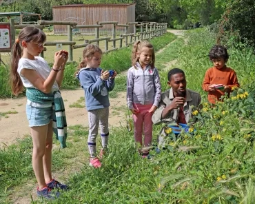 Un groupe d'enfants et leur animateur prennent des fleurs en photos