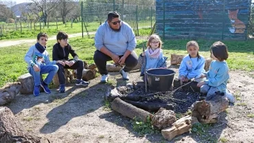un groupe d'enfants et leur animateur sont autour d'un feu de camp éteint