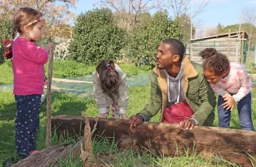 un animateur et trois enfants soulèvent une planche au jardin