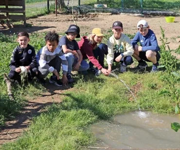 Un groupe d'enfants rempli une petite mare avec un tuyau