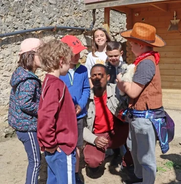 Un groupe d'enfants et leur animateur observent une poule.