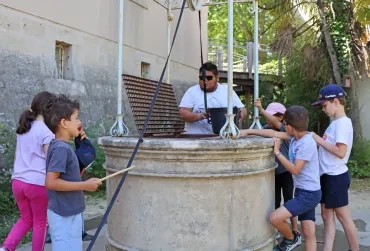 un groupe d'enfants et leur animateur sont autour d'un puits