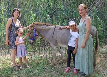 deux mamans et leur fille posent devant un âne