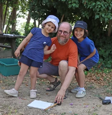 un père et ses deux enfants posent avec un maillet