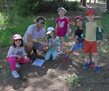 un groupe d'enfants et leur animateur montrent des boites à loupe
