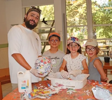 un groupe d'enfants et leur animateur montrent une boule de papier mâché