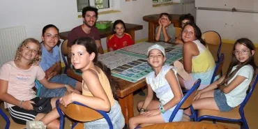 Un groupe d'enfants et leur animateur sont autour d'un grand panneau avec des cartes