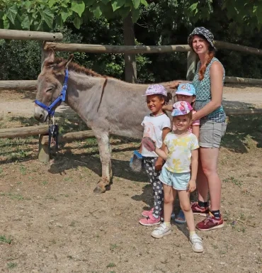 3 enfants et leur animatrice sont à côté d'un âne