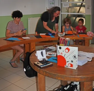 Deux enfants et deux adultes dessinent et découpent