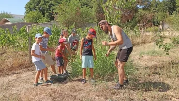 Un groupe d'enfants et leur animateur récolte de l'herbe