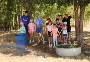 Un groupe d'enfants et leurs animateurs remplissent une grosse bassine d'eau