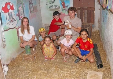 Un groupe d'enfants et leurs animateurs posent dans un enclos et observent un cochon d'Inde