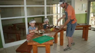 Munis de tabliers et de charlottes un animateur et deux enfants préparent la chapelure pour le crumble