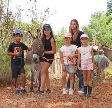 Un groupe d'enfants et leur animatrice posent avec un âne