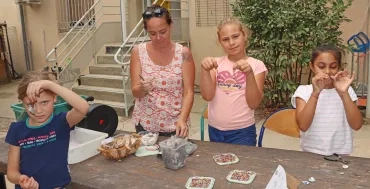 Un groupe d'enfants et leur animatrice montrent des boucles d'oreilles