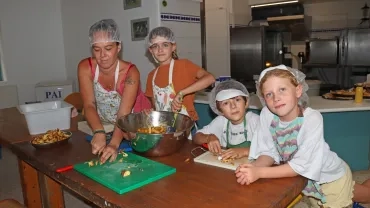 Un groupe d'enfants et leur animatrice coupent des pommes de terre