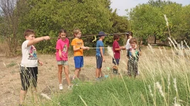 Un groupe d'enfants dans la nature avec des cannes à pêche en baton