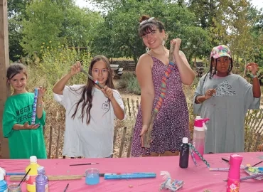 Un groupe d'enfants et leur animatrice posent avec leurs batons colorés