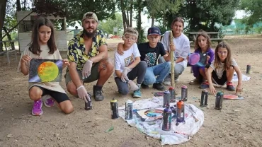 Un groupe d'enfants et un animateur posent avec des dessins et des bombes de peinture