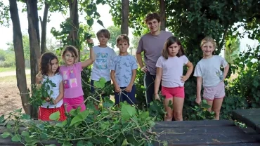 Un groupe d'enfants et un animateur posent avec des branches de lierre