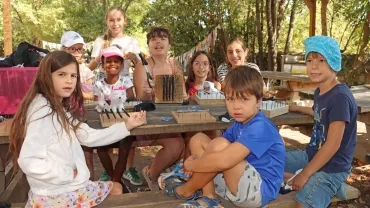 Un groupe d'enfants et leur animatrice posent des cadres à tisser