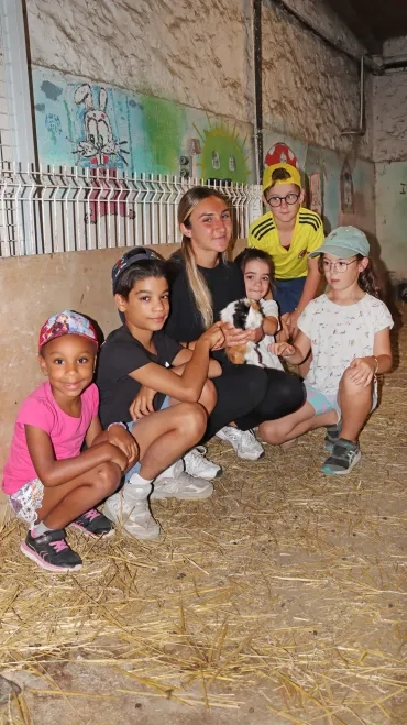 Un groupe d'enfants et une animatrice posent avec un cochon d'Inde