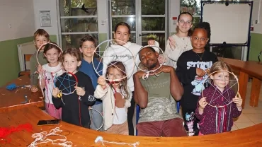un groupe d'enfants et leur animateur montrent des cerceaux de bois avec de la laine à l'intérieur
