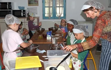 un groupe d'enfants et leur animatrice sont en cuisine en train de peser des aliments