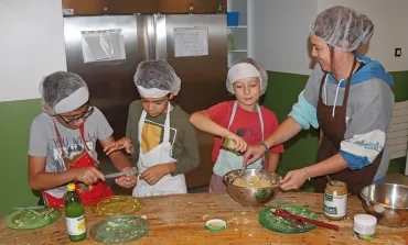 un groupe d'enfants et leur animatrice sont en cuisine en train de mélanger une préparation