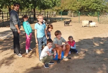 un groupe d'enfants et leur animateur posent dans l'enclos des chèvres