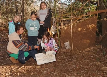 un groupe d'enfants et leur animatrice scient devant une cabane