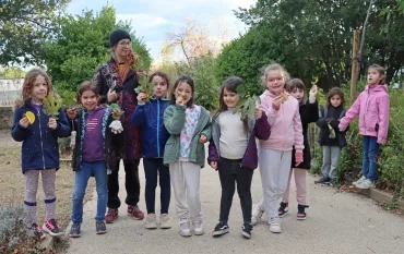 un groupe d'enfants et leur animatrice montrent les éléments naturels récoltés