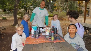 un groupe d'enfants et leur animateur montrent leurs réalisation avec des bombes de peinture