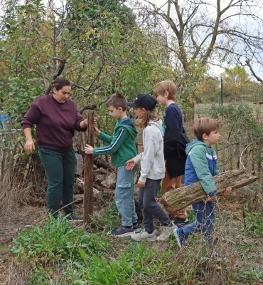 un groupe d'enfants et leur animatrice bricolent en extérieur