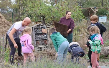 un groupe d'enfants et leurs animateurs observent un hotel à insectes