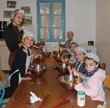 un groupe d'enfants et leur animatrice sont en cuisine avec des saladiers