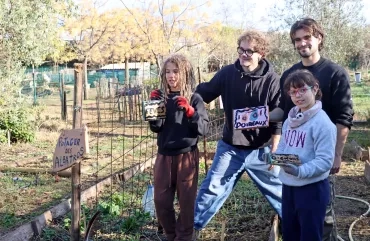 un groupe d'enfants et leurs animateurs montrent des panneaux en bois avec écrit le nom des légumes plantés