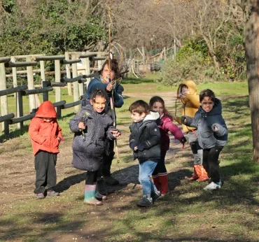 un groupe d'enfants et leur animatrice posent avec un arc en bois