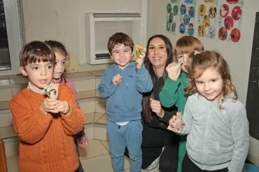 un groupe d'enfants et leur animatrice montrent des cartons colorés