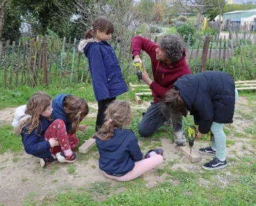 Un groupe d'enfants et leur animateur sont au sol avec des perceuses et des morceaux de bois