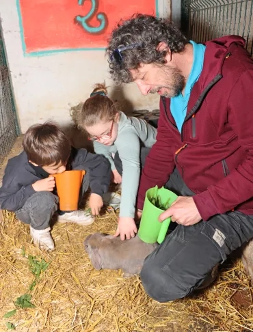 deux enfants et leur animateur caressent un lapin