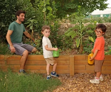 un groupe d'enfants et leur animateur arrosent des plantes